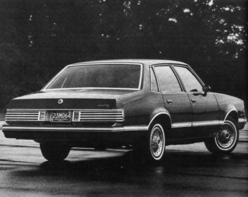 Classic sedan with a sleek rear design, parked on a wet road.