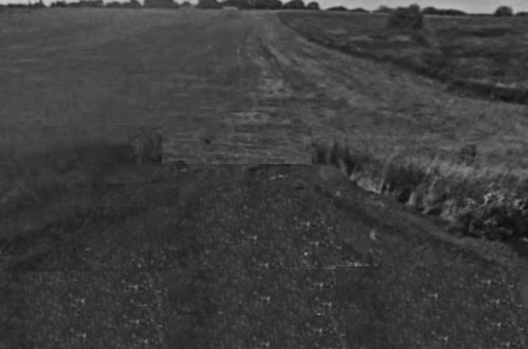 A barren field with a distant horizon and slight elevation changes.